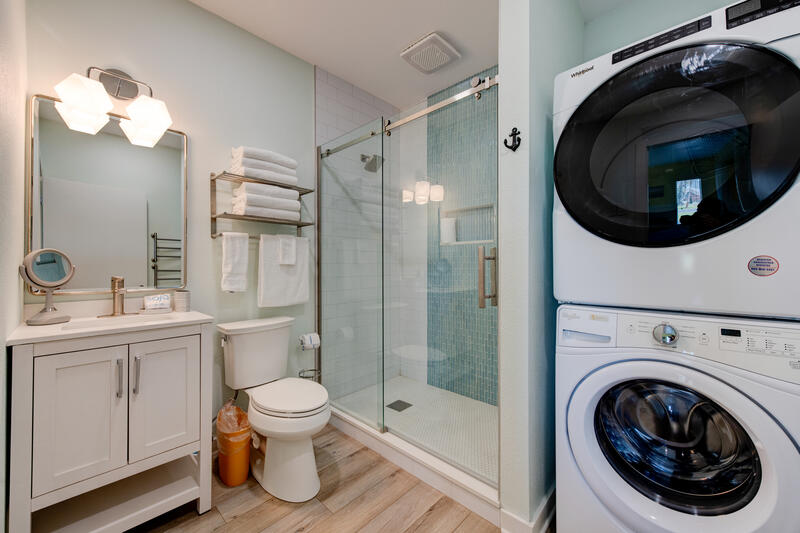First-floor bathroom with walk-in shower and stacked washer and dryer